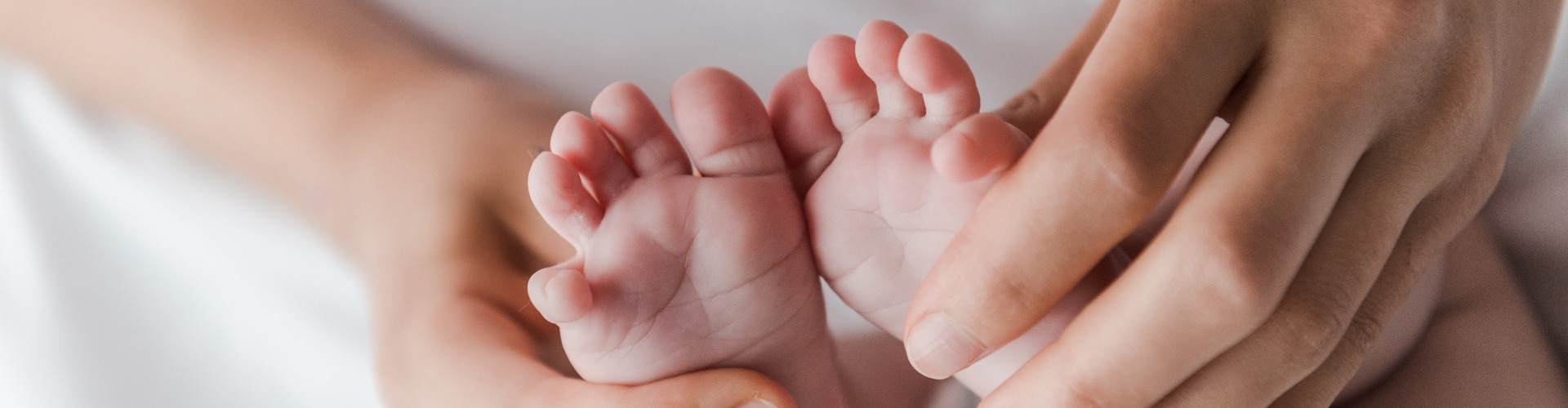 panoramic shot of woman doing massage while touching legs of infant baby